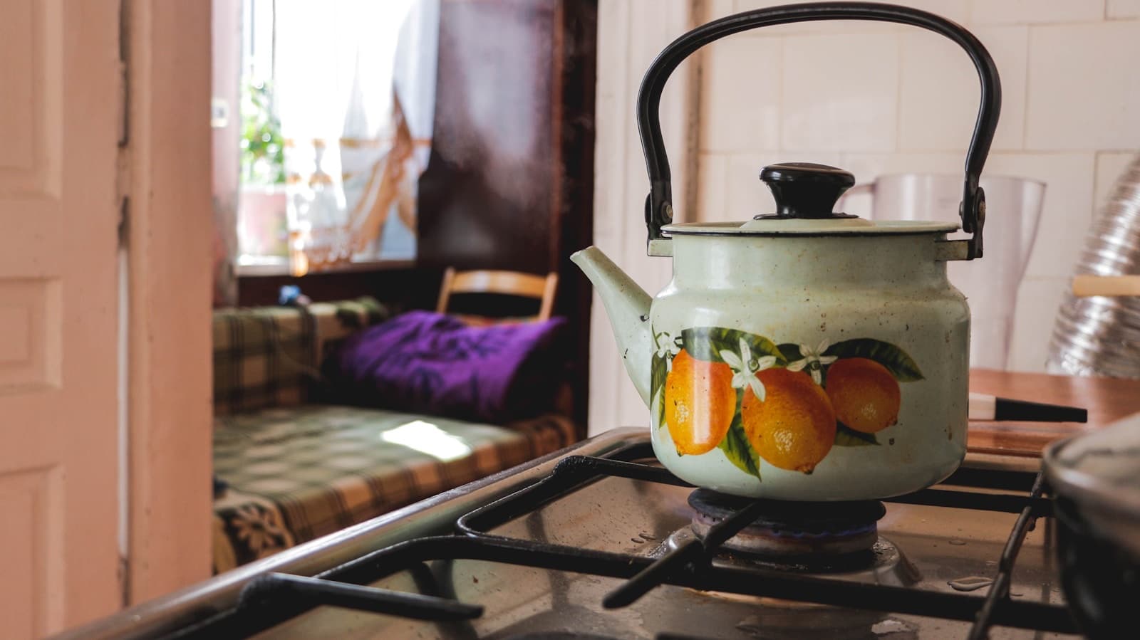 Steaming kettle on a gas stove with morning sun through the kitchen window