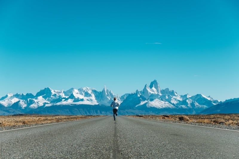 Man running on a road toward mountains