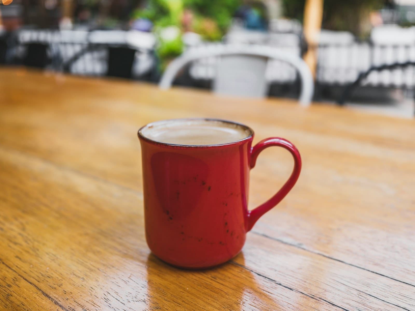 Red mug of coffee on a wooden café table