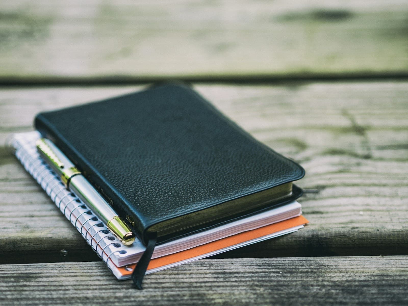 Stack of unused journals with a pen on weathered wood